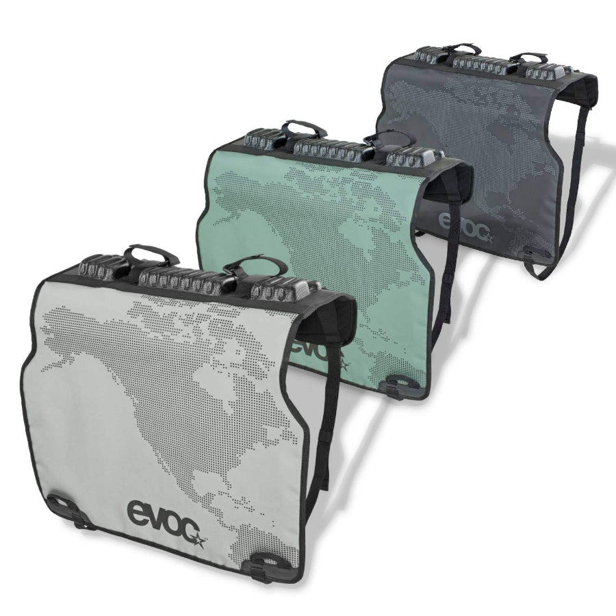 Three EVOC tailgate pads in gray, green, and black colors designed for securing bikes during truck transport, displayed vertically.