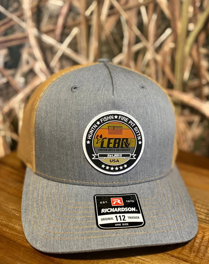 Grey and amber trucker hat with a round rubber patch