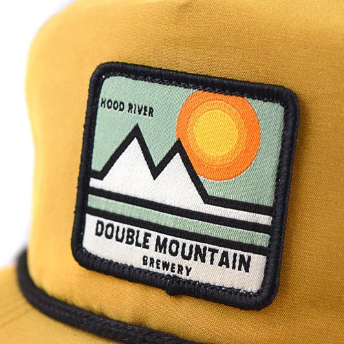 Close-up of a stitched embroidered patch on a mustard rope hat